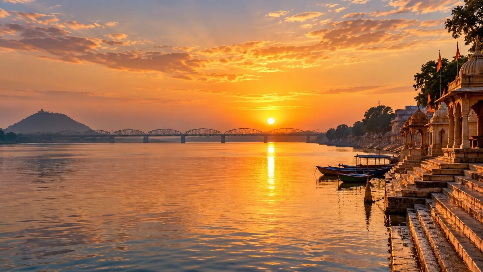 Sunrise over the Godavari River with stone ghats and boats along the riverbank